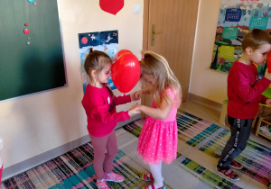 Dziewczynki tańczą w parach z serduszkowym balonem między głowami.